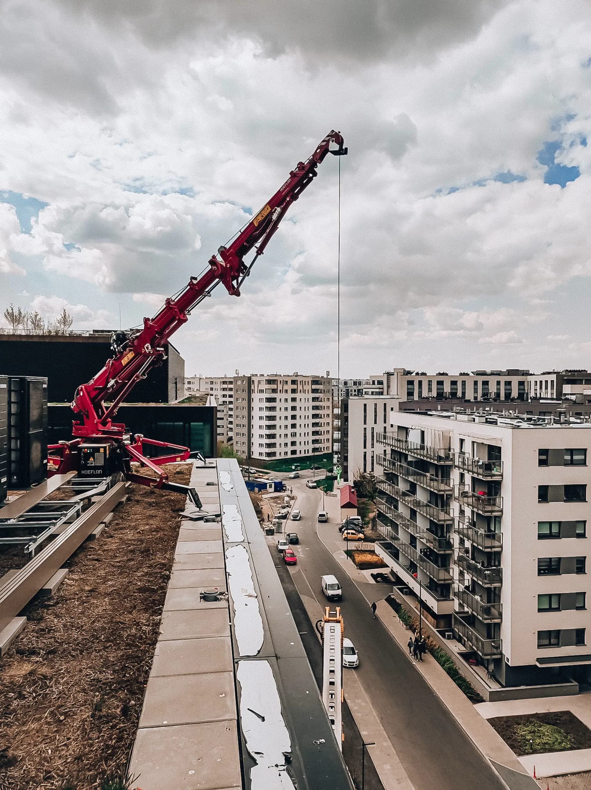 Grúa Hoeflon levantando algo desde el techo de un edificio.