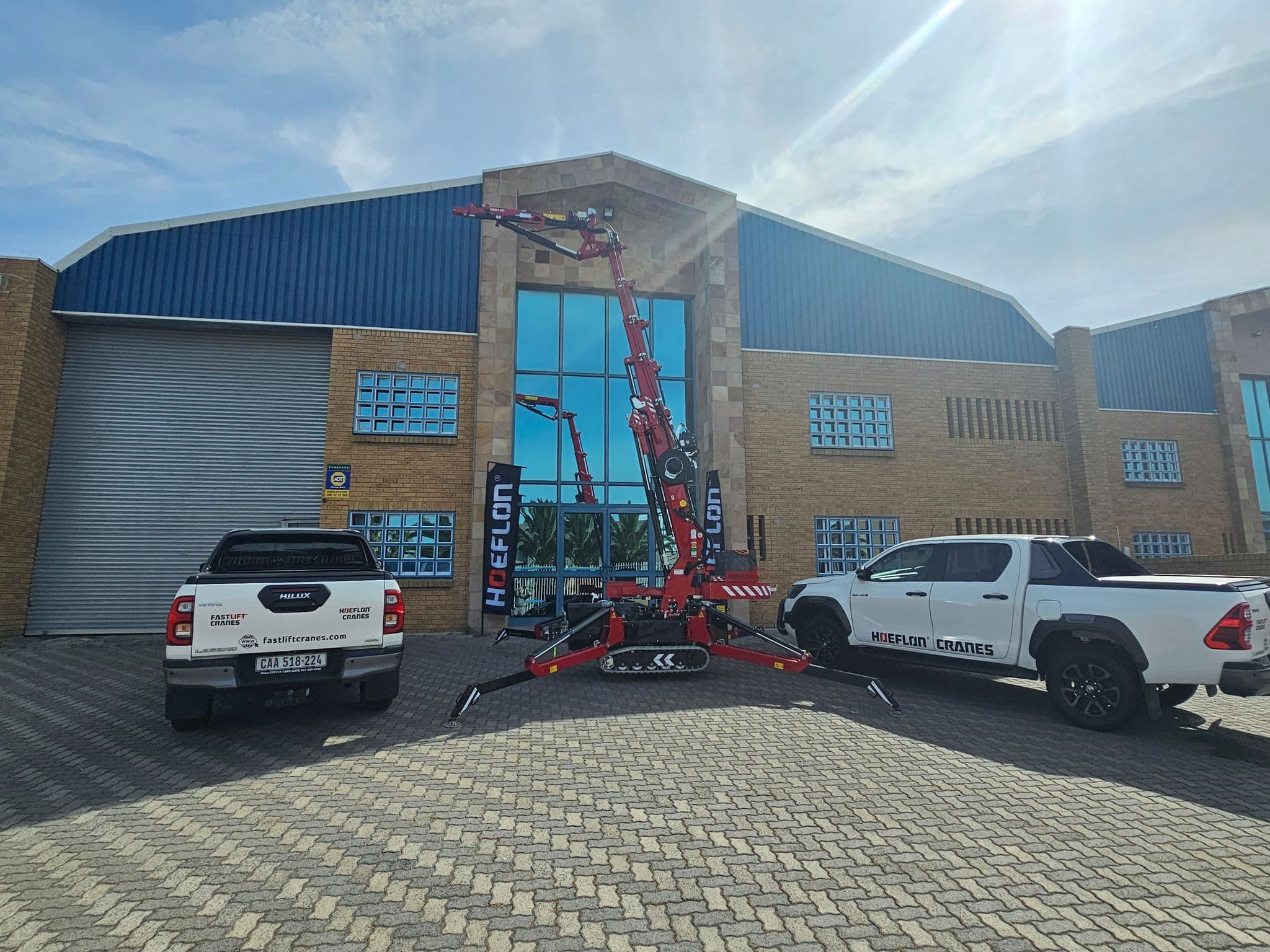 Grúa Hoeflon fuera de un edificio con dos vehículos de Fastlift Cranes.