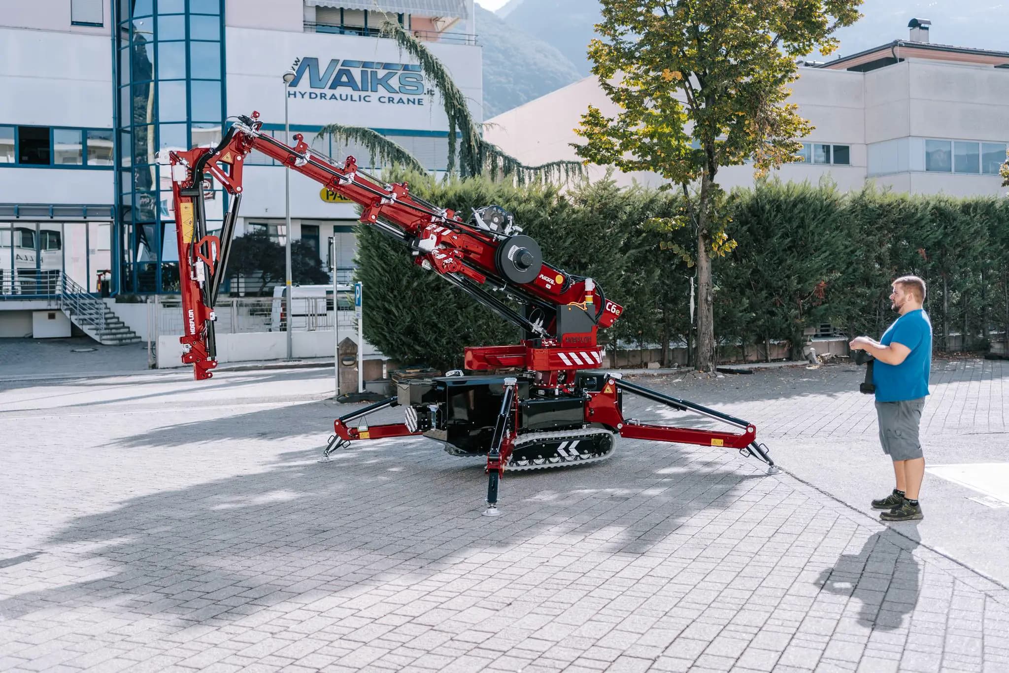 Grúa Hoeflon en acción afuera, hombre controla la grúa con panel remoto.