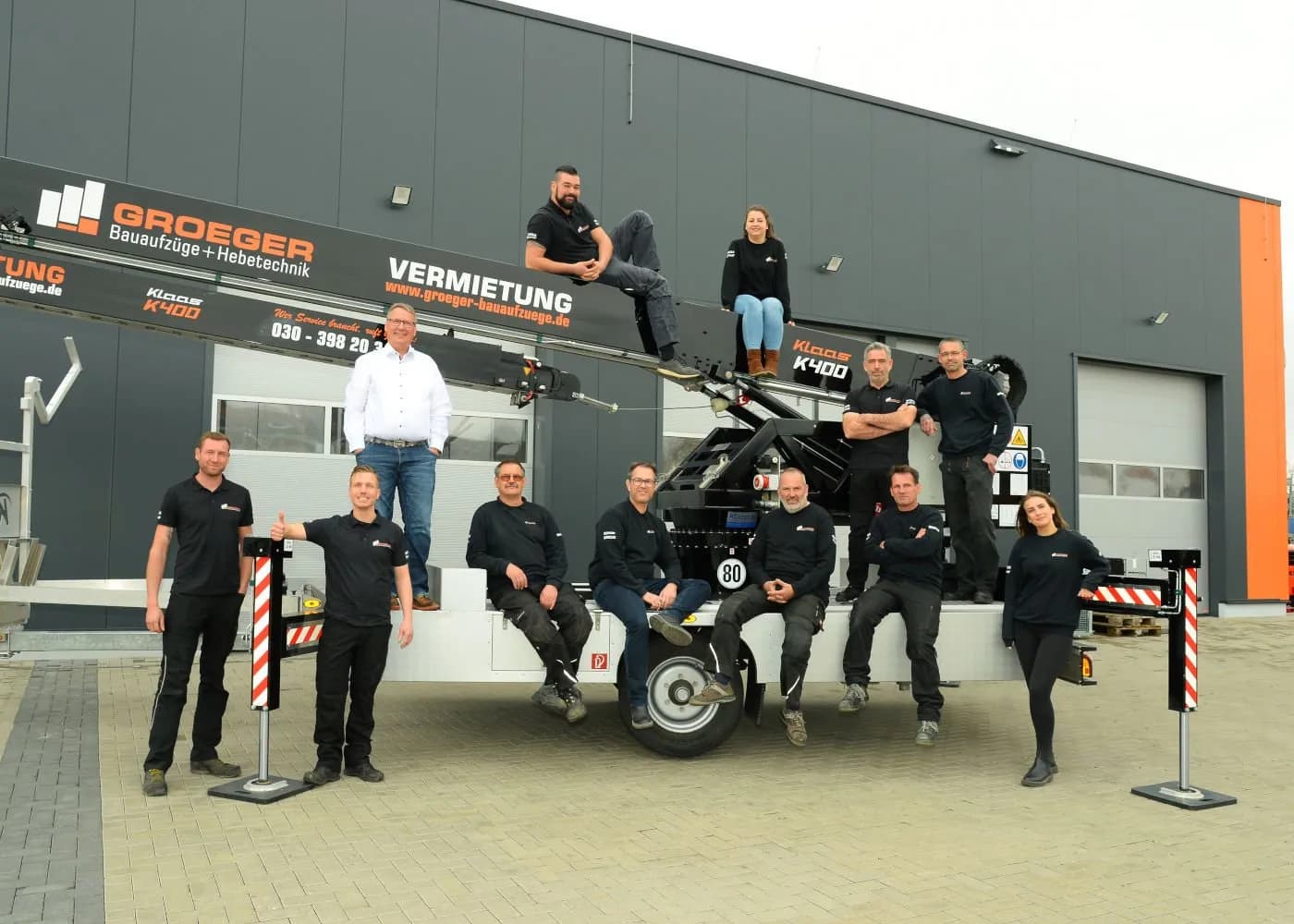 Foto del equipo de Groeger Bauaufzüge con grúa al fondo.