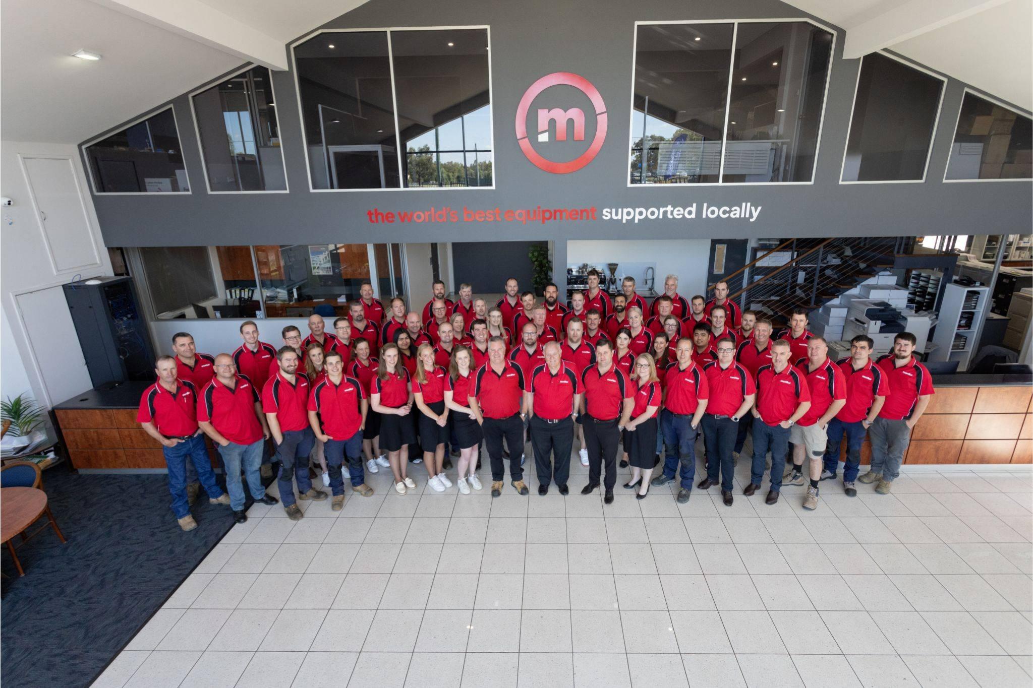Foto de grupo del equipo de Monitor con camisas rojas en una oficina.