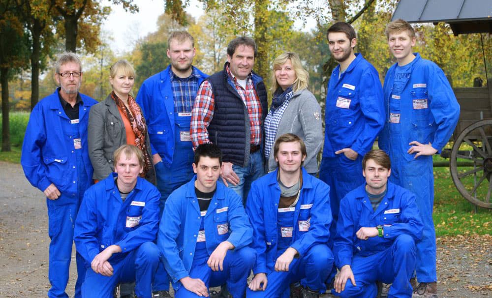 Foto de grupo de empleados con monos azules, al aire libre en la naturaleza.