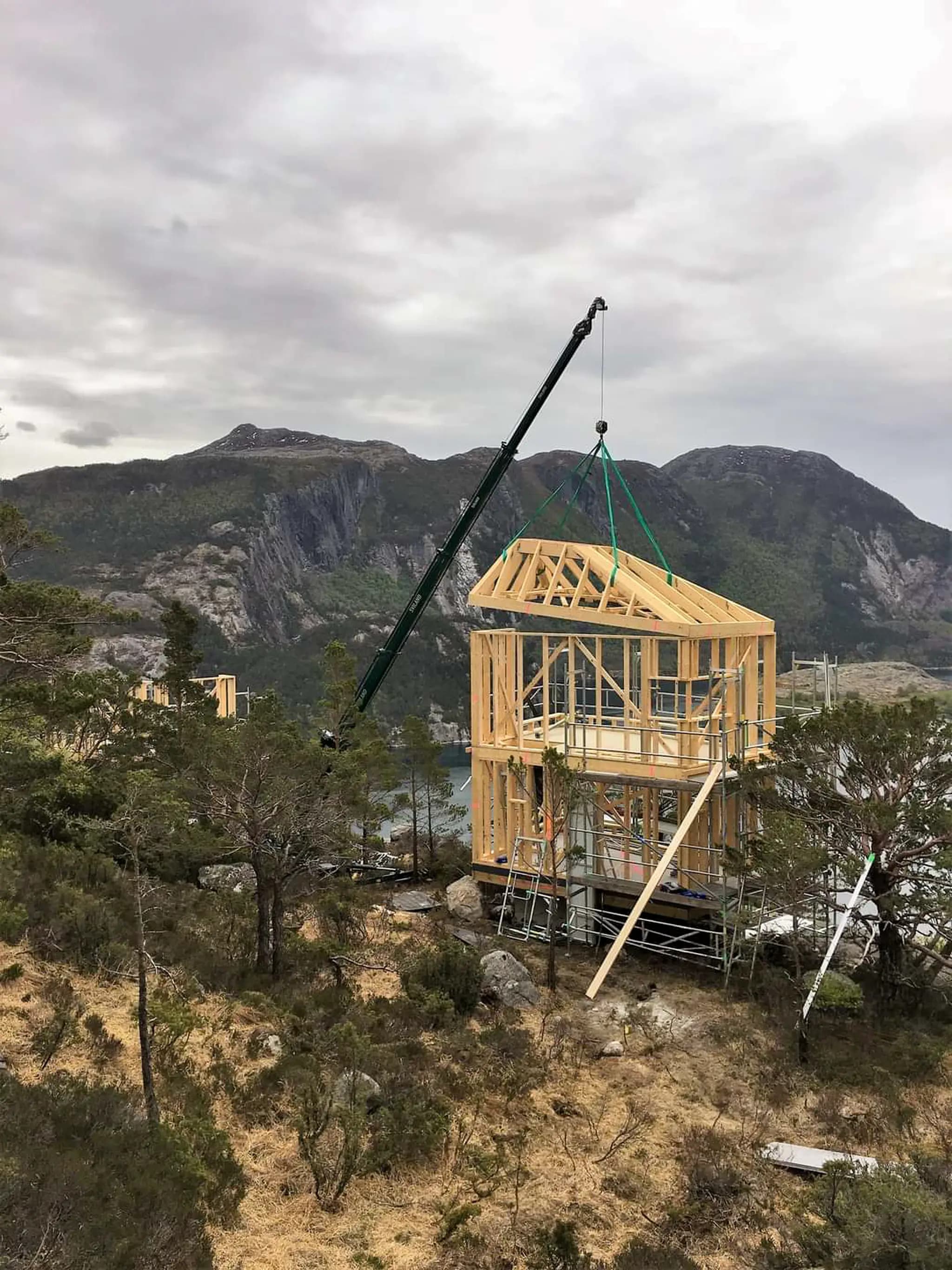 Hoeflon C6e levantando un marco de madera en Noruega con montañas al fondo.
